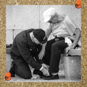 Servant leadership photo shows man serving woman by helping tie her shoes.