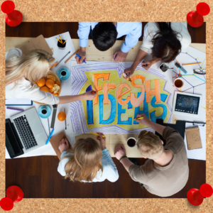 A creative team works around a table on a poster with the words, "fresh ideas" drawn out.