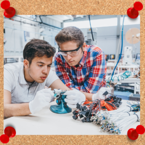 Two men work on a project together with wires and electrical components.