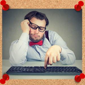 A lazy coworker sleeps at his desk with glasses askew and a finger on his computer keyboard.