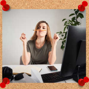 Photo is a woman sitting at her desk and balancing a pencil on her upper lip rather than working.