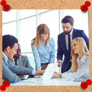 Image shows employees communicating over an office conference table.